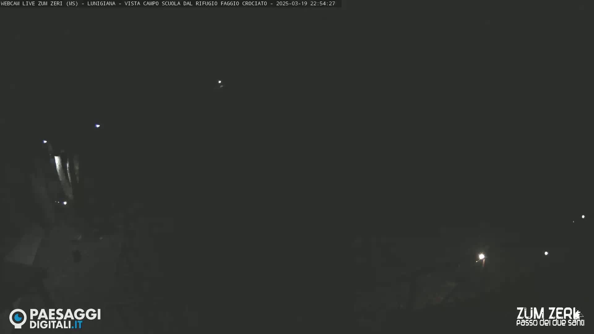 A nighttime, low-light view of a dark area with a few distant lights visible.