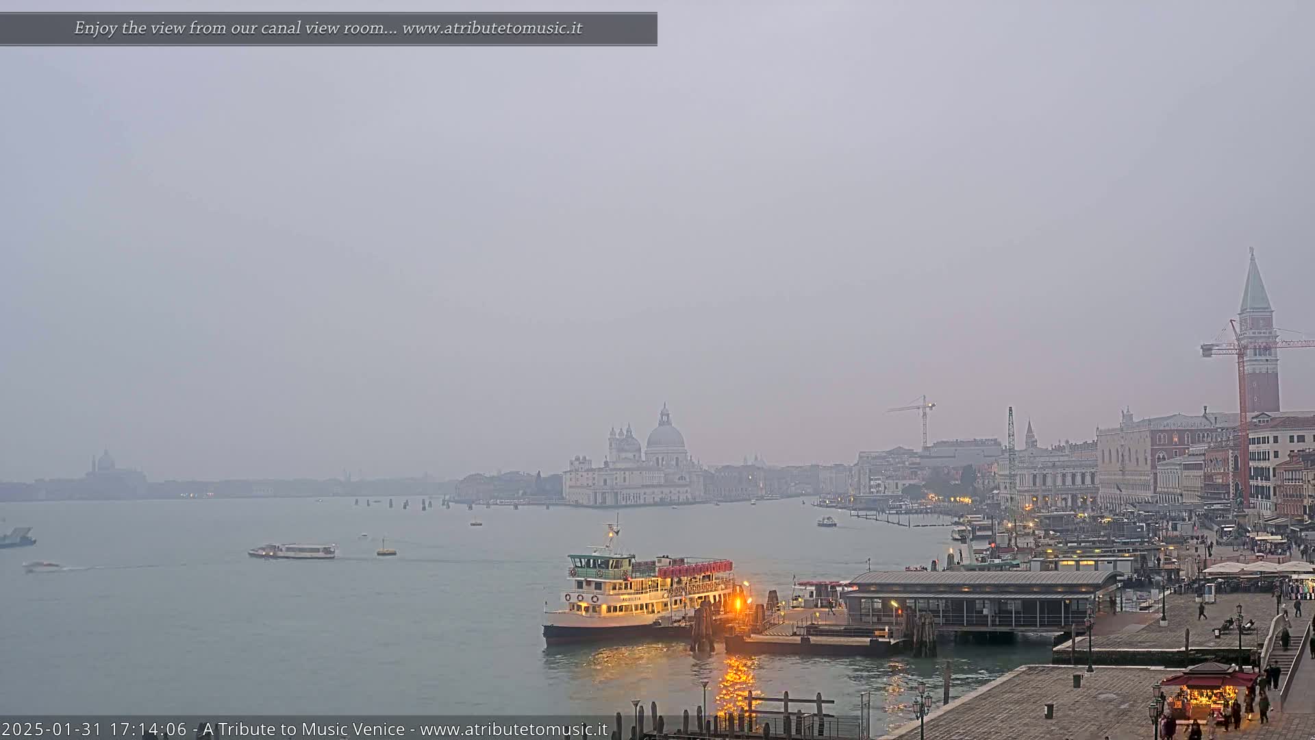 A ferry approaches a dock in a hazy Venetian canal, with the Basilica di Santa Maria della Salute visible in the distance.