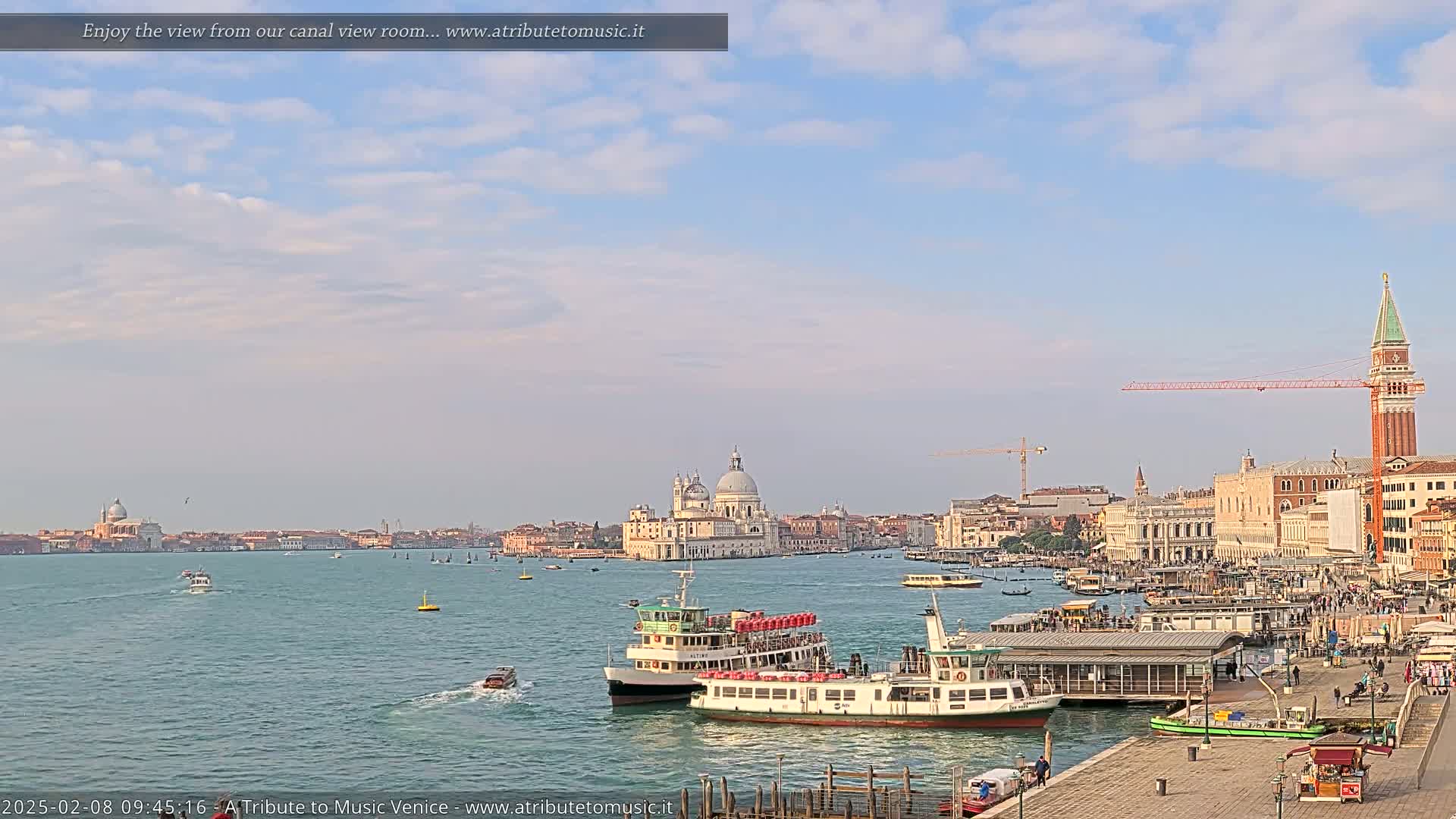 A Venetian cityscape with a partly cloudy sky, showing several boats on a canal with the Basilica di Santa Maria della Salute prominent in the middle distance.