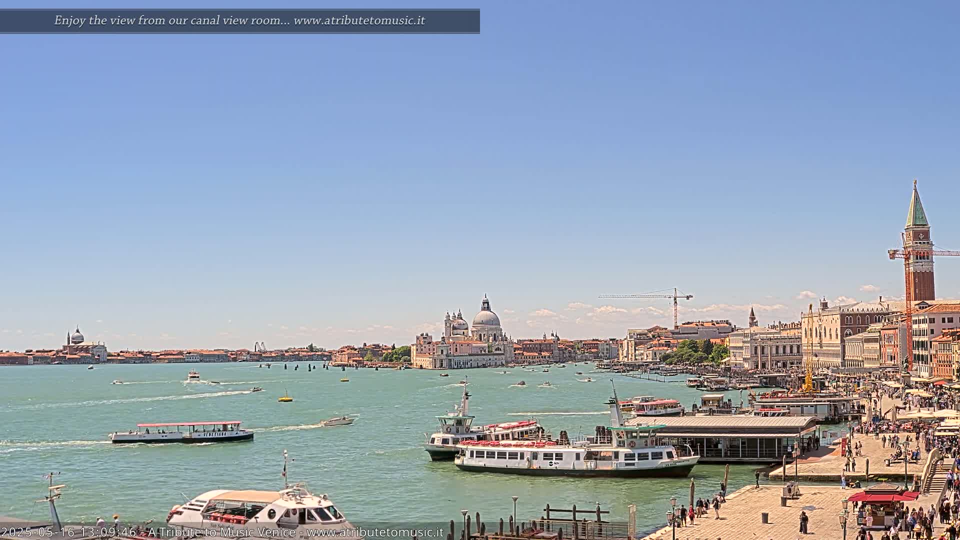 A sunny Venetian waterway scene shows several water taxis and passenger boats near a dock, with the Basilica di Santa Maria della Salute and St. Mark's Campanile in the background.
