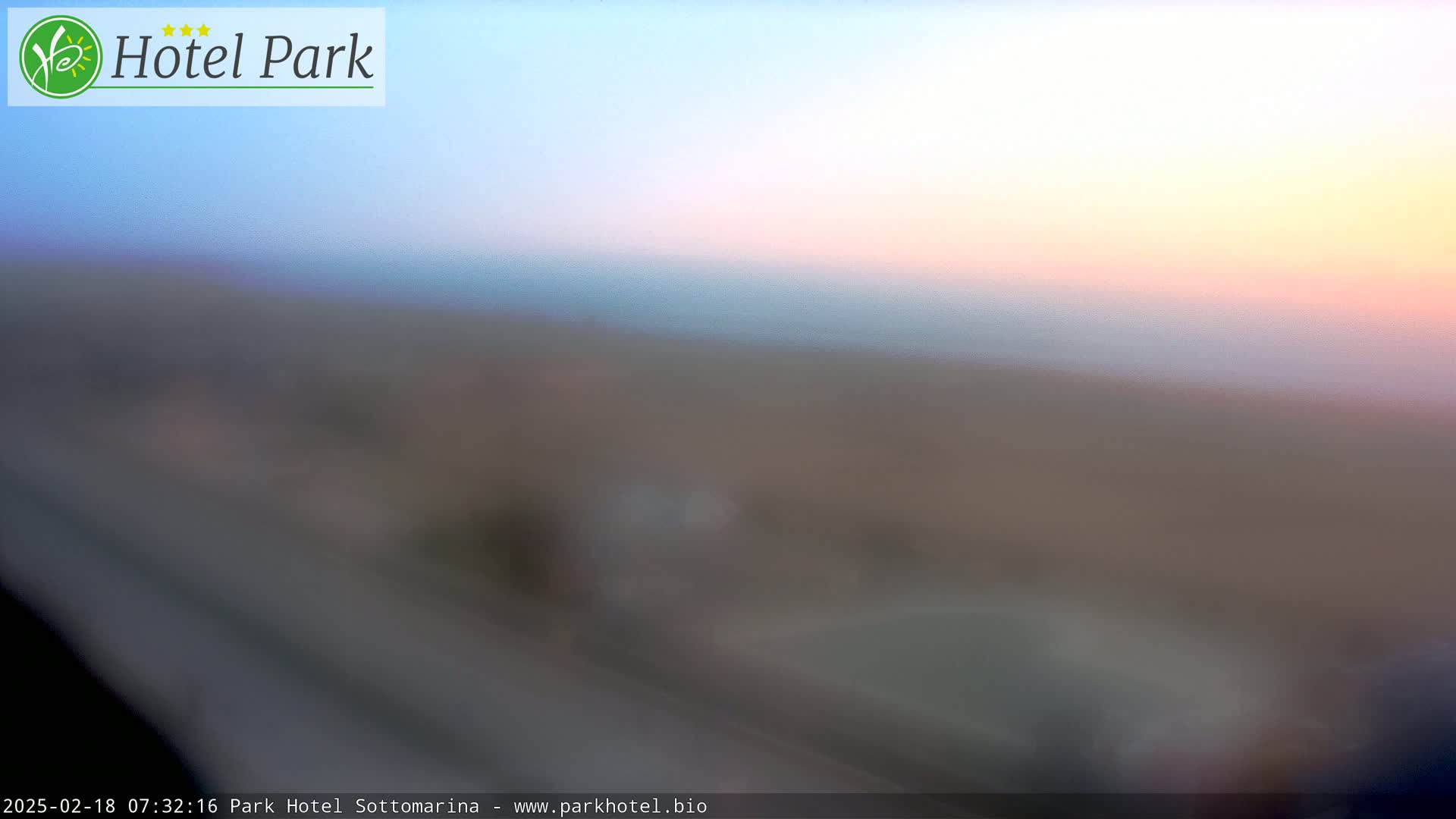 A blurry, out-of-focus image shows a muted sunrise over a flat, brown landscape.