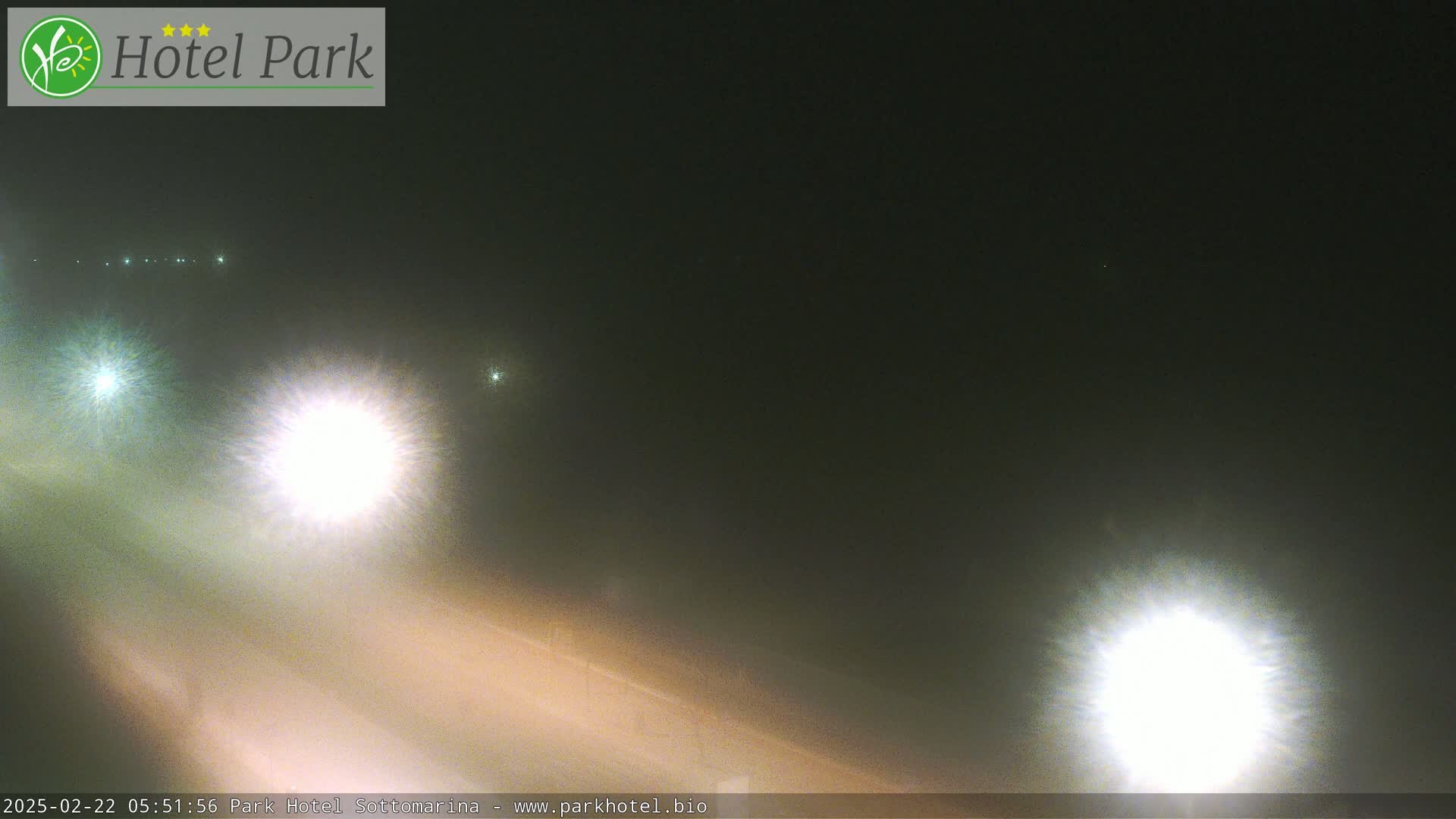 Headlights of vehicles are visible on a foggy road at night.