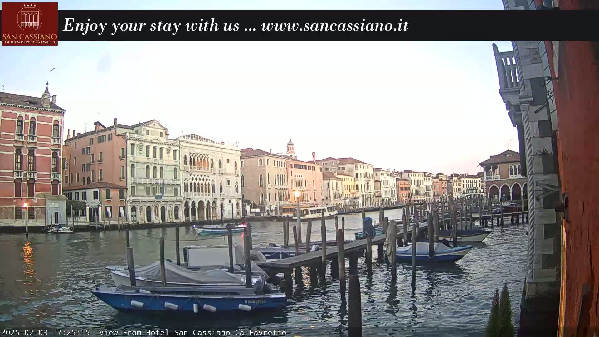 A canal in Venice, Italy, at dusk, is lined with colorful buildings and several moored boats.