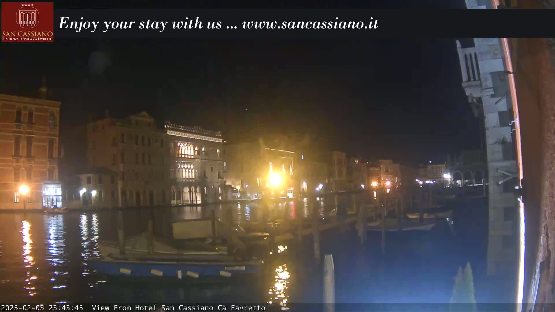 A nighttime view of a canal in Venice, with buildings illuminated along the waterway.