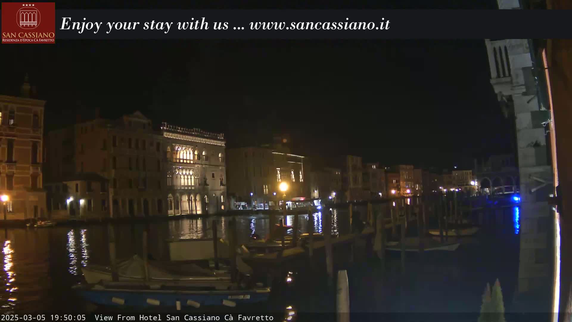 A nighttime view of illuminated buildings and boats along a canal.