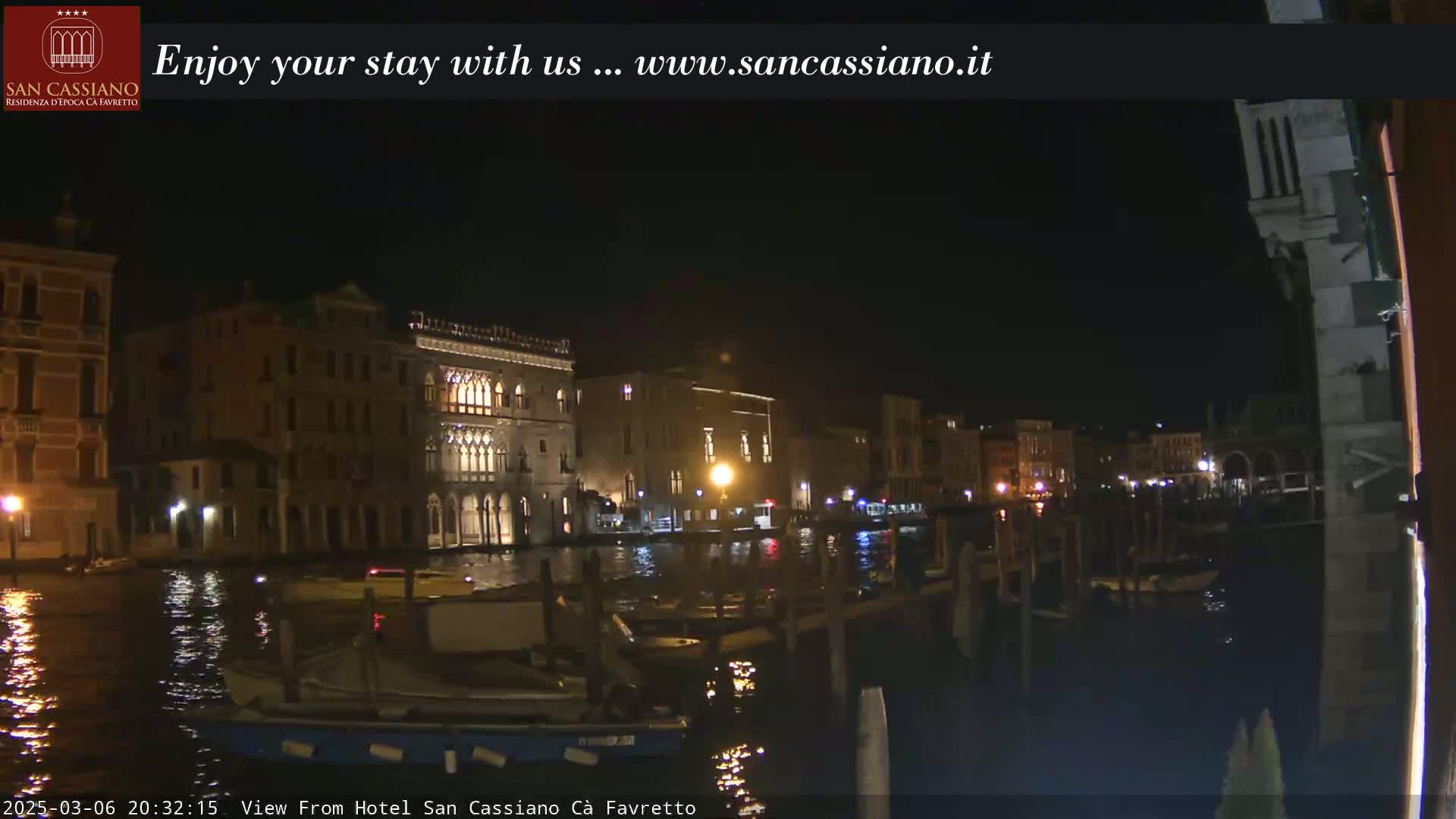 A nighttime view of illuminated buildings along a calm canal in Venice.