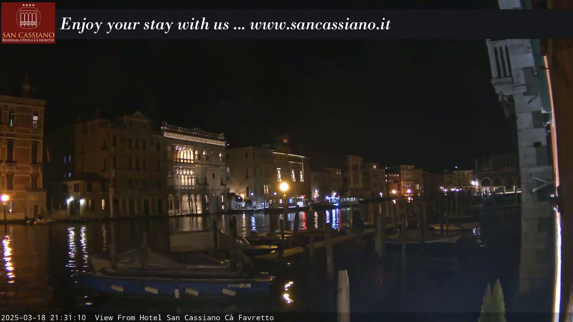 At night, a canal reflects the lights of buildings lining its banks.