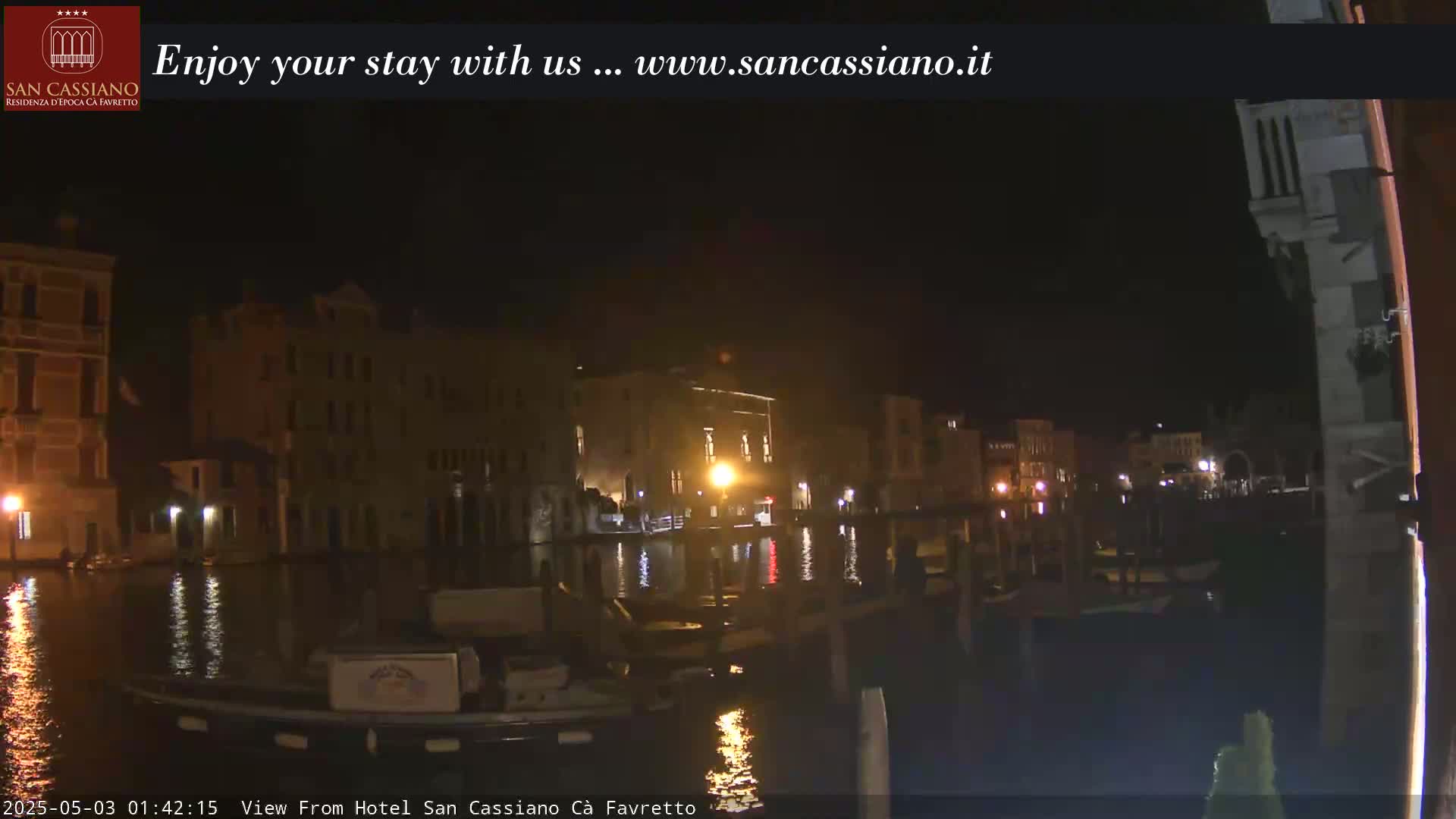 At night, a canal reflects the illuminated buildings lining its banks.