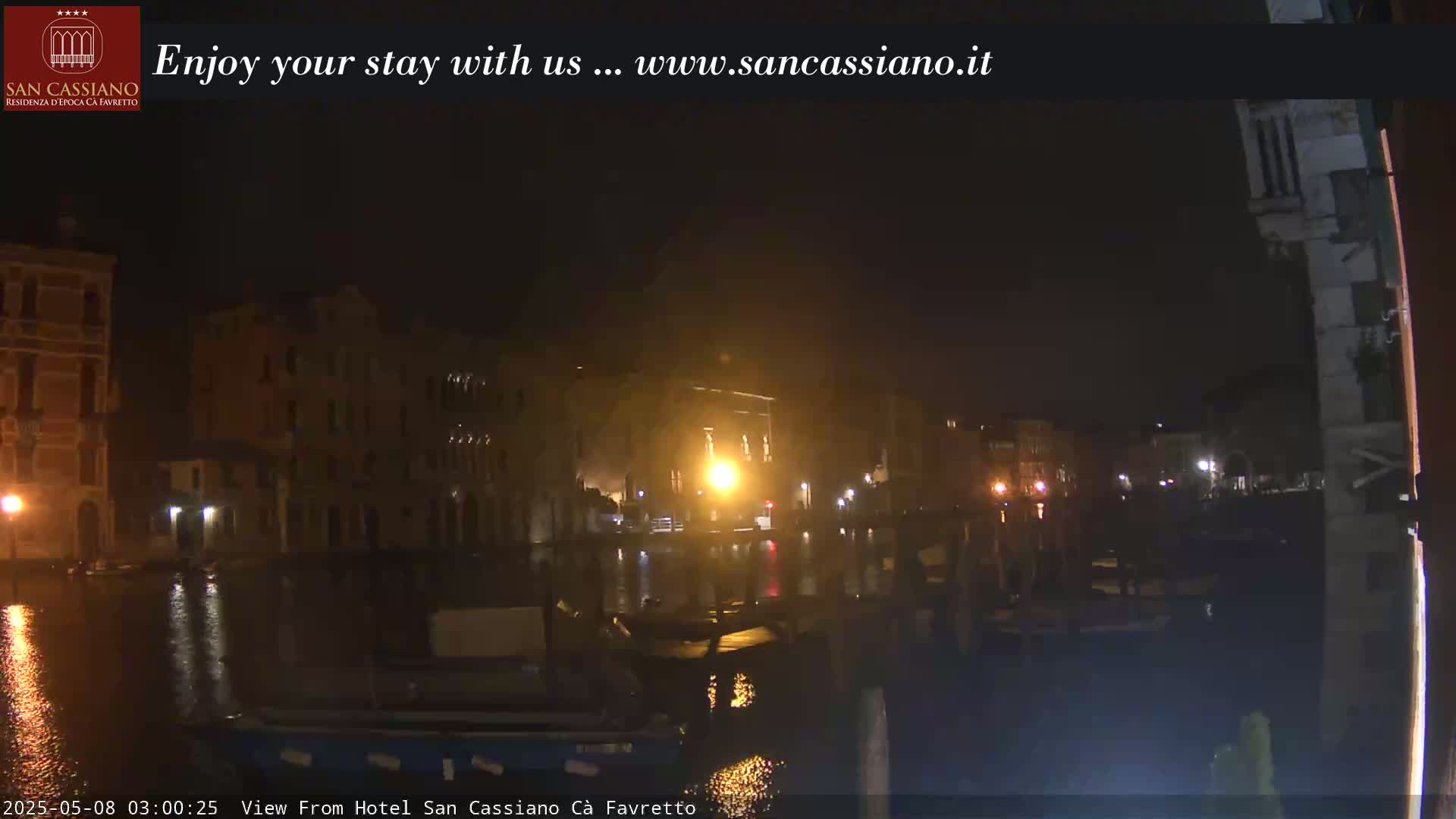 A nighttime view of a canal in Venice, with buildings illuminated along the waterway.