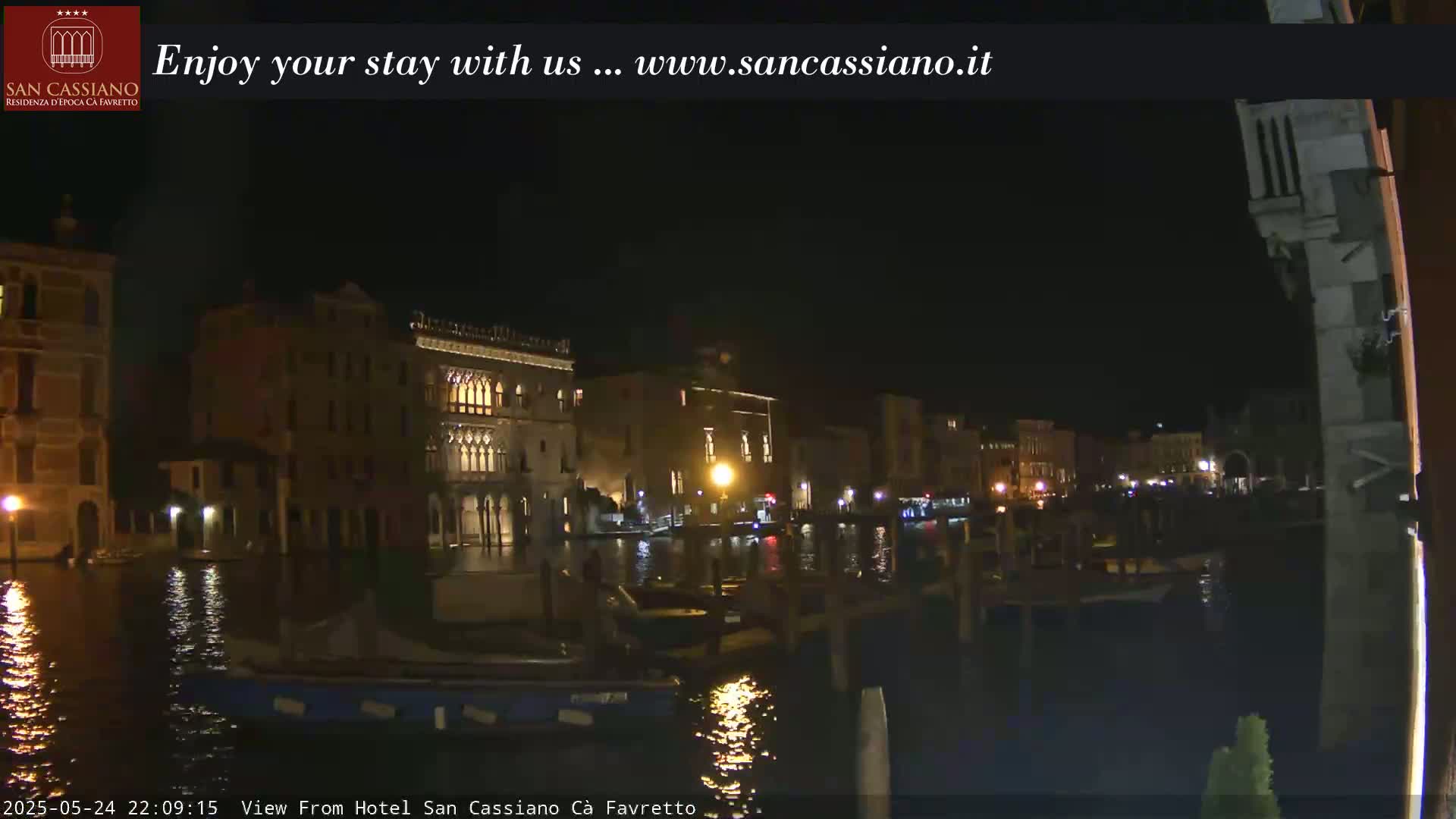 Nighttime view of a canal in Venice, Italy, with illuminated buildings along the waterway and several boats moored.