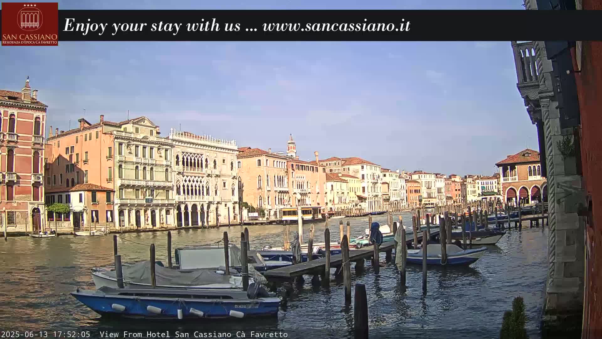 A sunny day in Venice shows a canal lined with colorful buildings and numerous moored boats.