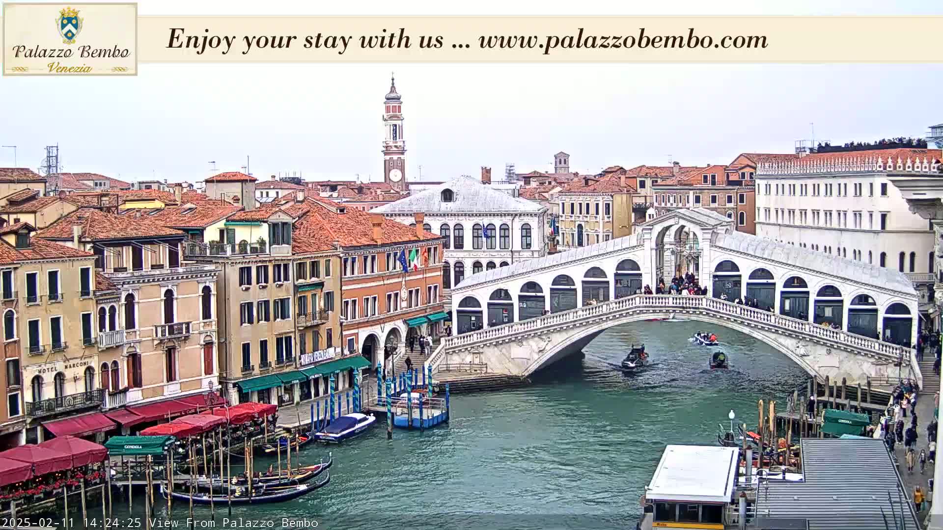 A Venetian canal scene on an overcast day shows a bridge with pedestrians and boats on the water, with buildings lining the canal.