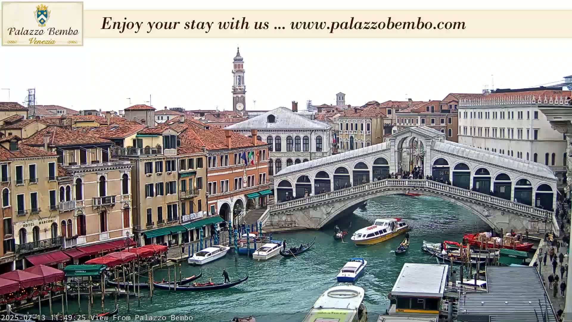 A view of the Rialto Bridge in Venice, Italy, on an overcast day, with numerous boats and buildings lining the canal.