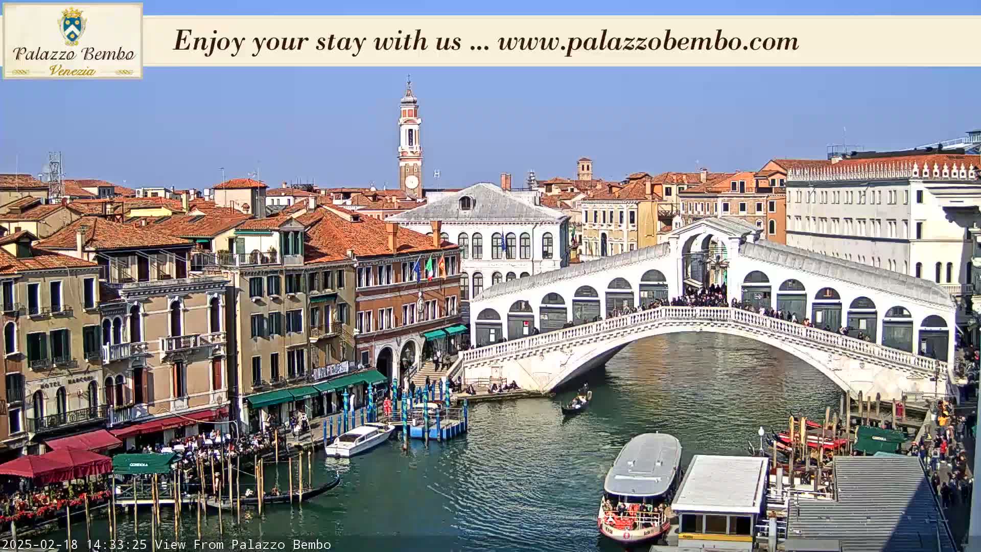 A sunny day in Venice shows a canal with boats, the Rialto Bridge crowded with people, and colorful buildings lining the waterway.