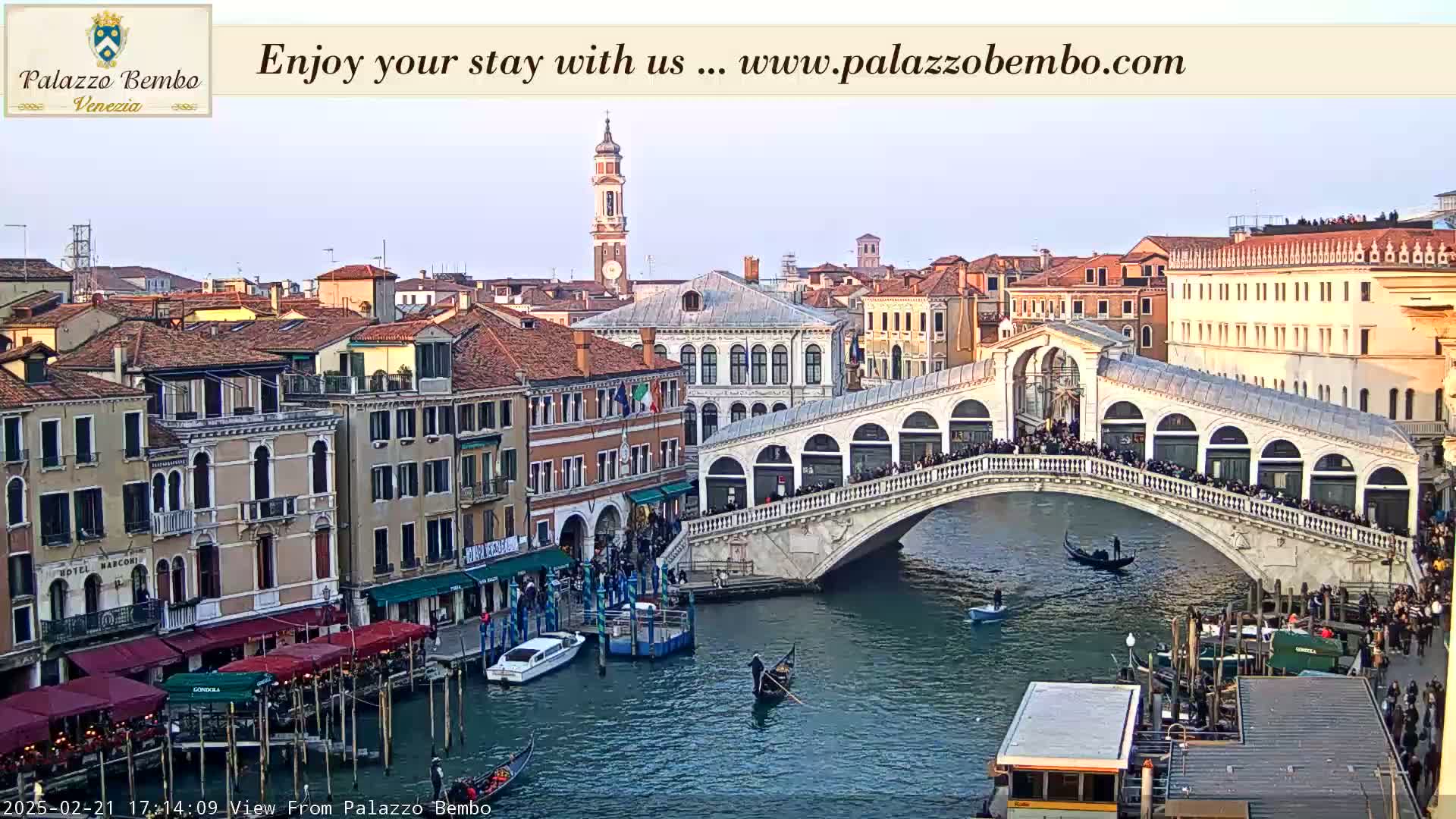 A Venetian canal scene shows a bridge crowded with people, gondolas on the water, and buildings lining the waterway under a twilight sky.