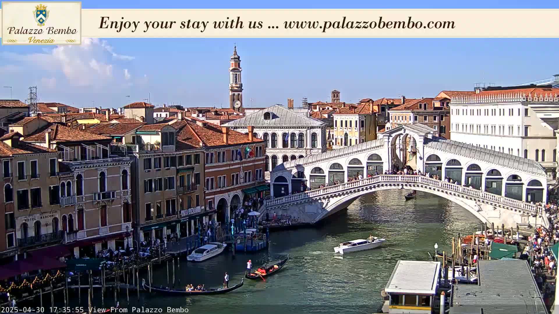 A sunny Venetian cityscape shows a canal with gondolas, boats, and the Rialto Bridge crowded with people.