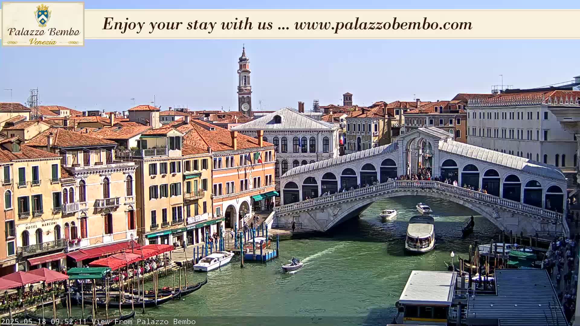 A sunny Venetian cityscape shows a canal with gondolas, boats, and the Rialto Bridge, with numerous buildings lining the waterway.