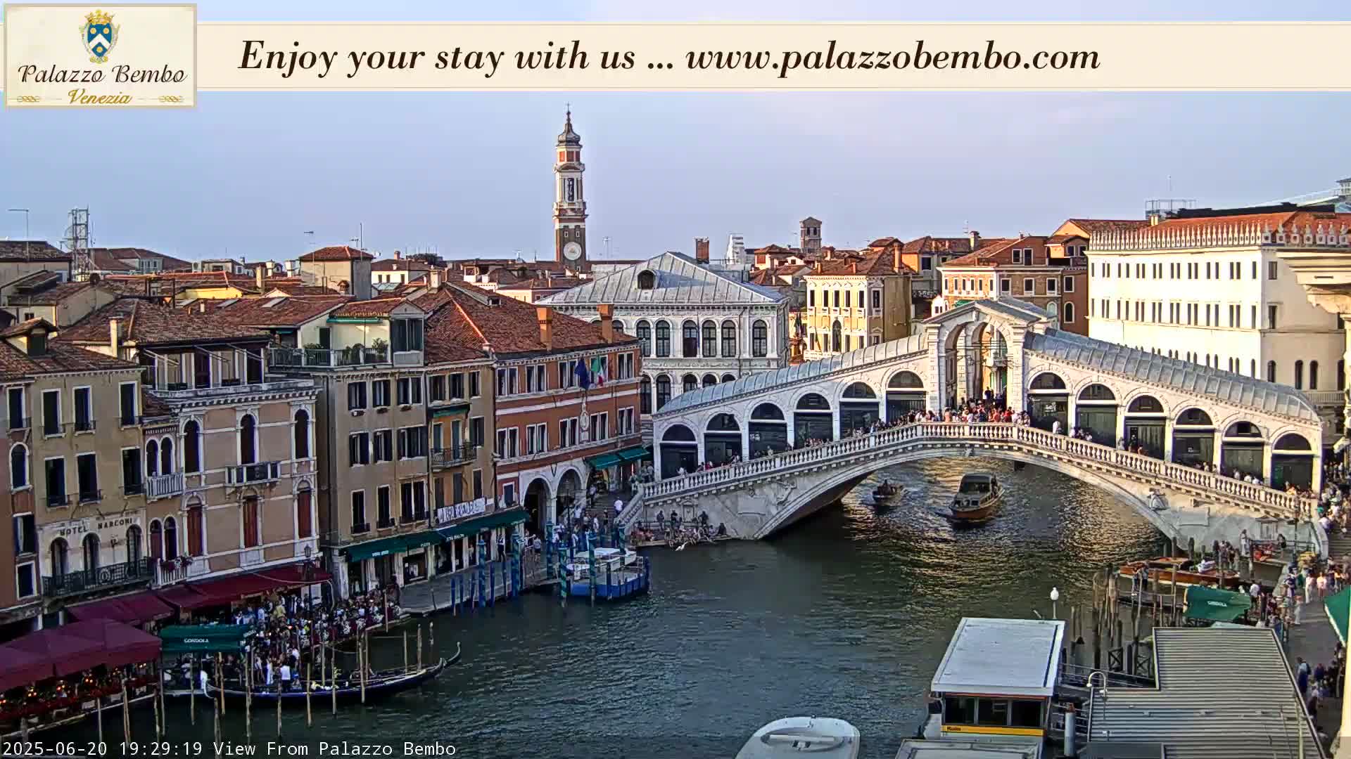 A Venetian bridge spans a canal lined with buildings, under a clear evening sky.