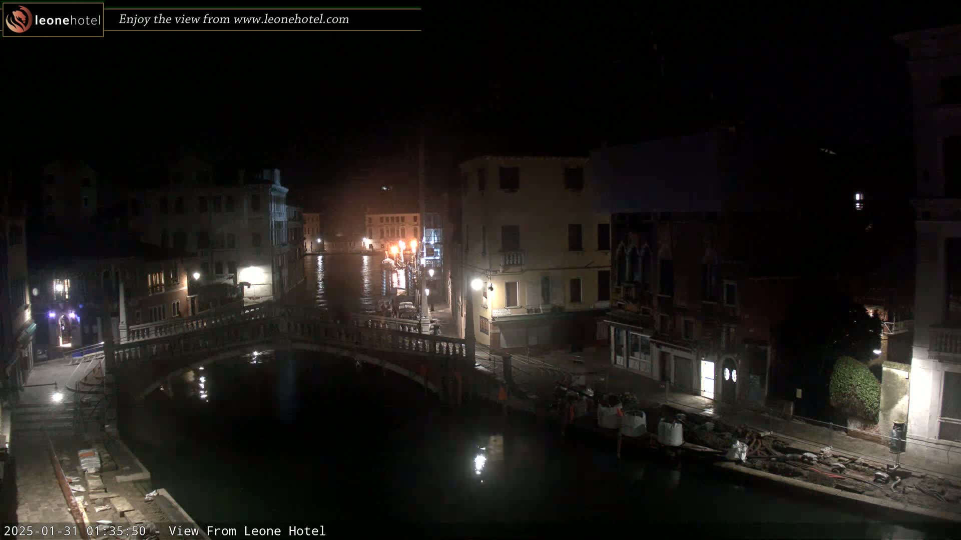 A nighttime view of a canal in Venice, showing buildings lining the waterway and a bridge spanning the canal.