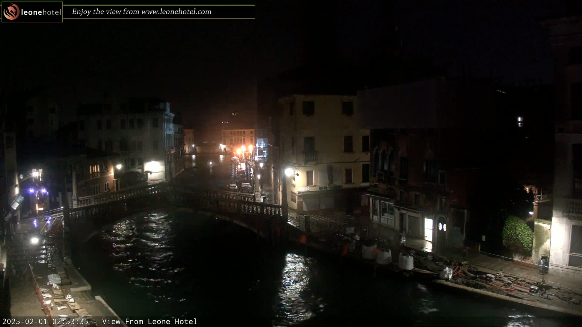 A nighttime view of a canal in Venice, showing bridges and buildings along its banks, with dark, rippling water under a seemingly clear sky.