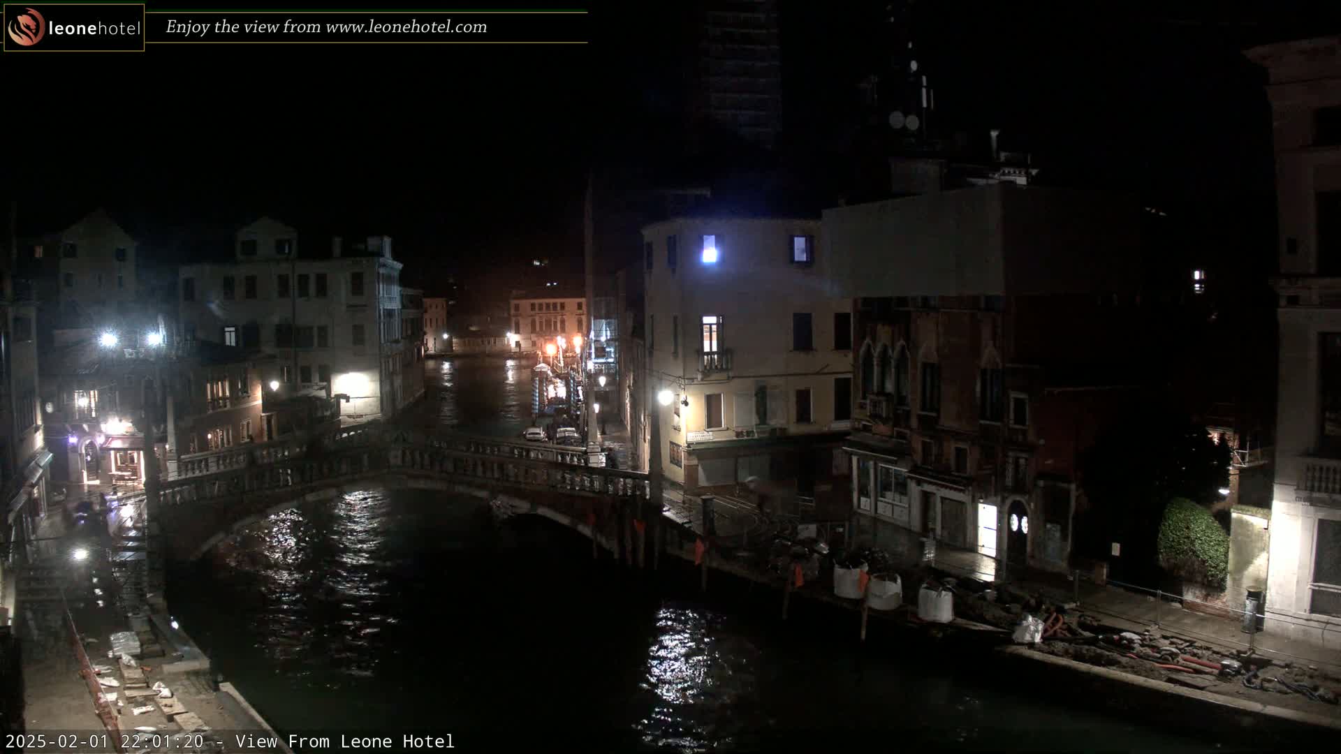 A nighttime view of a canal in Venice, with a bridge and buildings lining its banks, under dark, possibly overcast conditions.