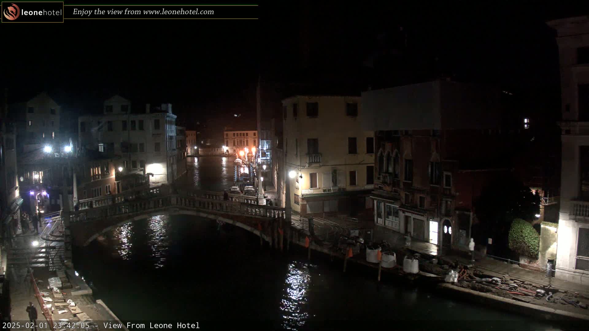 A nighttime view of a canal in Venice, showing a bridge, buildings along the waterway, and construction materials on the canal bank.