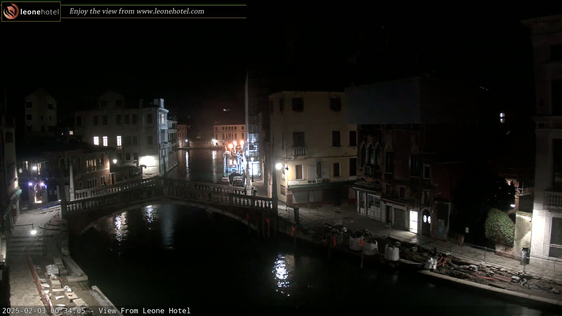 A nighttime view of a canal in Venice, showing a bridge and buildings along the waterway, under a dark sky.