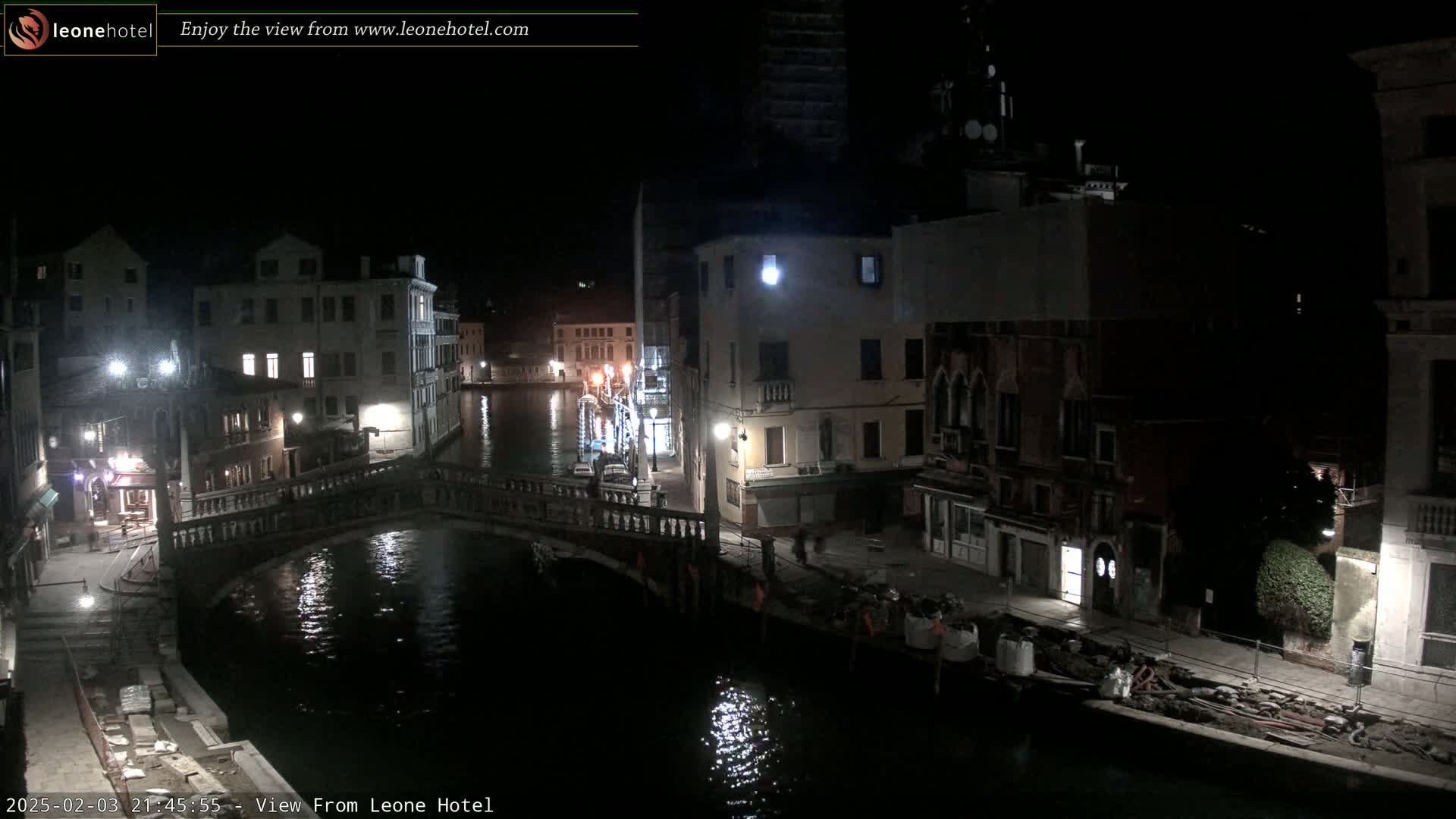 A nighttime view of a canal in Venice, Italy, with bridges, buildings, and dimly lit streets.