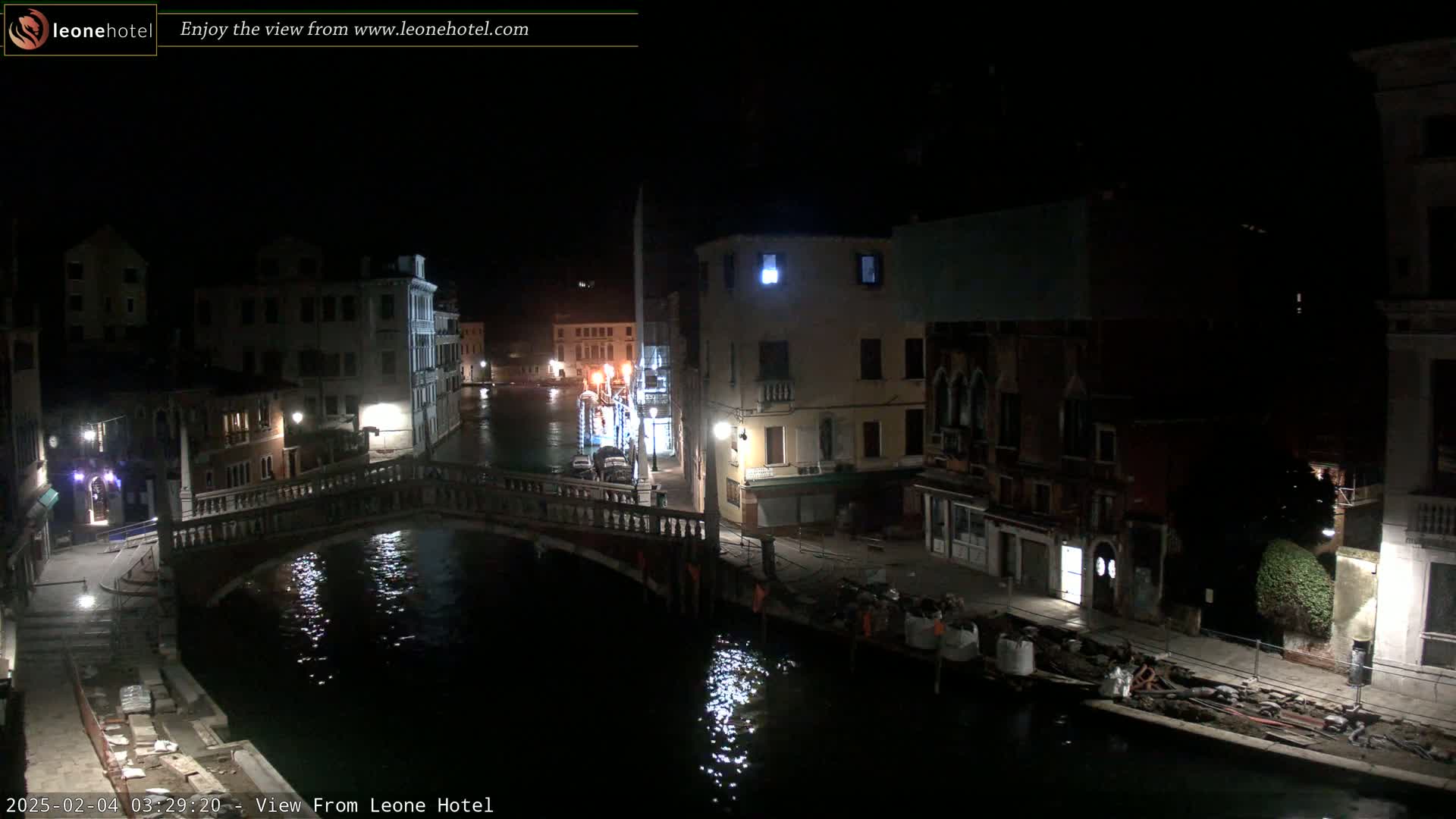 A nighttime view of a canal in Venice, Italy, showing bridges, buildings, and calm water.
