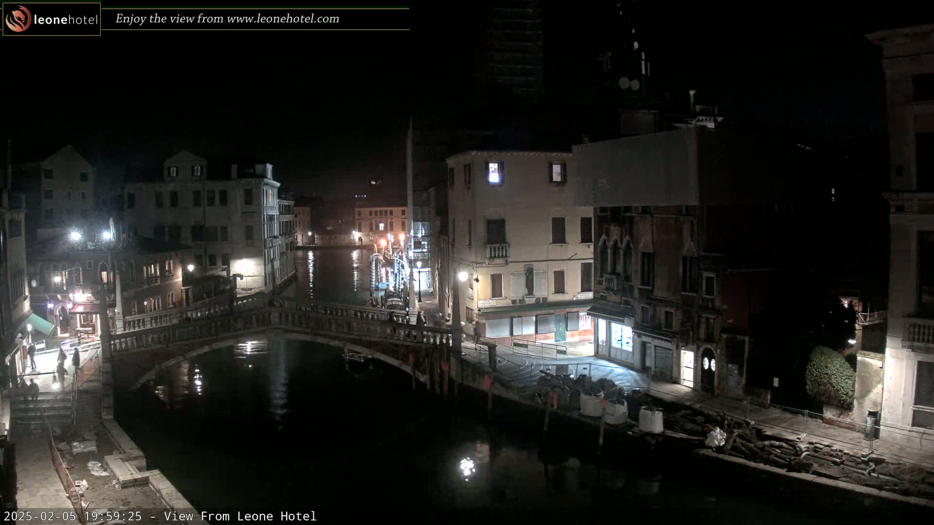 A nighttime view of a canal in Venice, showing bridges, buildings, and calm water.