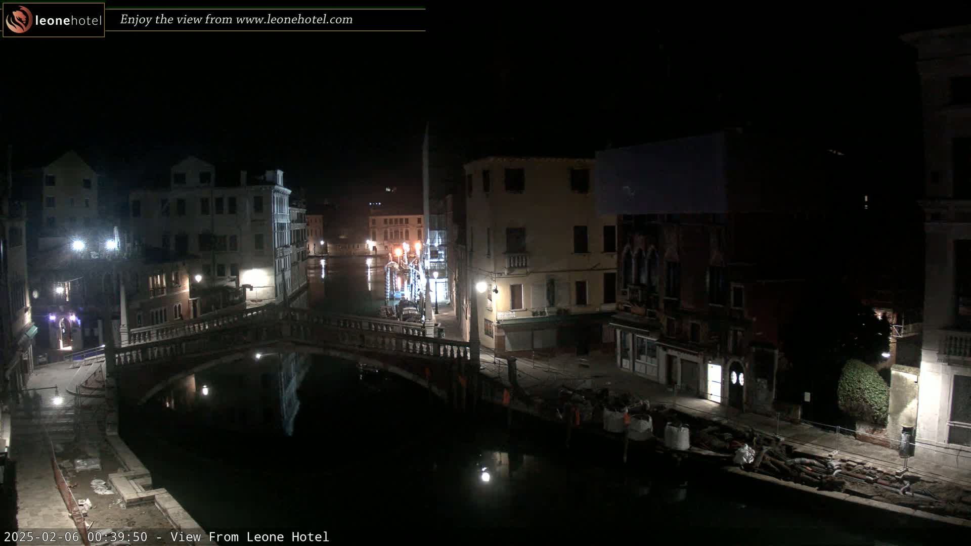 A nighttime view of a canal in Venice, Italy, showing bridges, buildings, and calm water reflecting the lights.