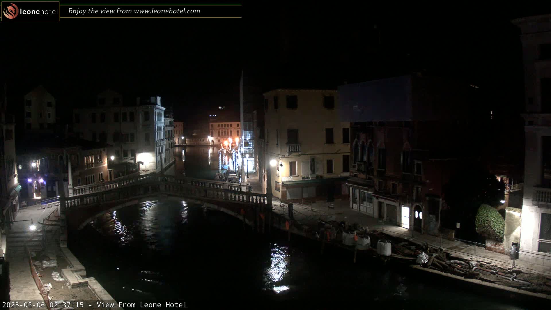A nighttime view of a canal in Venice, Italy, showing a bridge and buildings along the waterway under dark, clear skies.