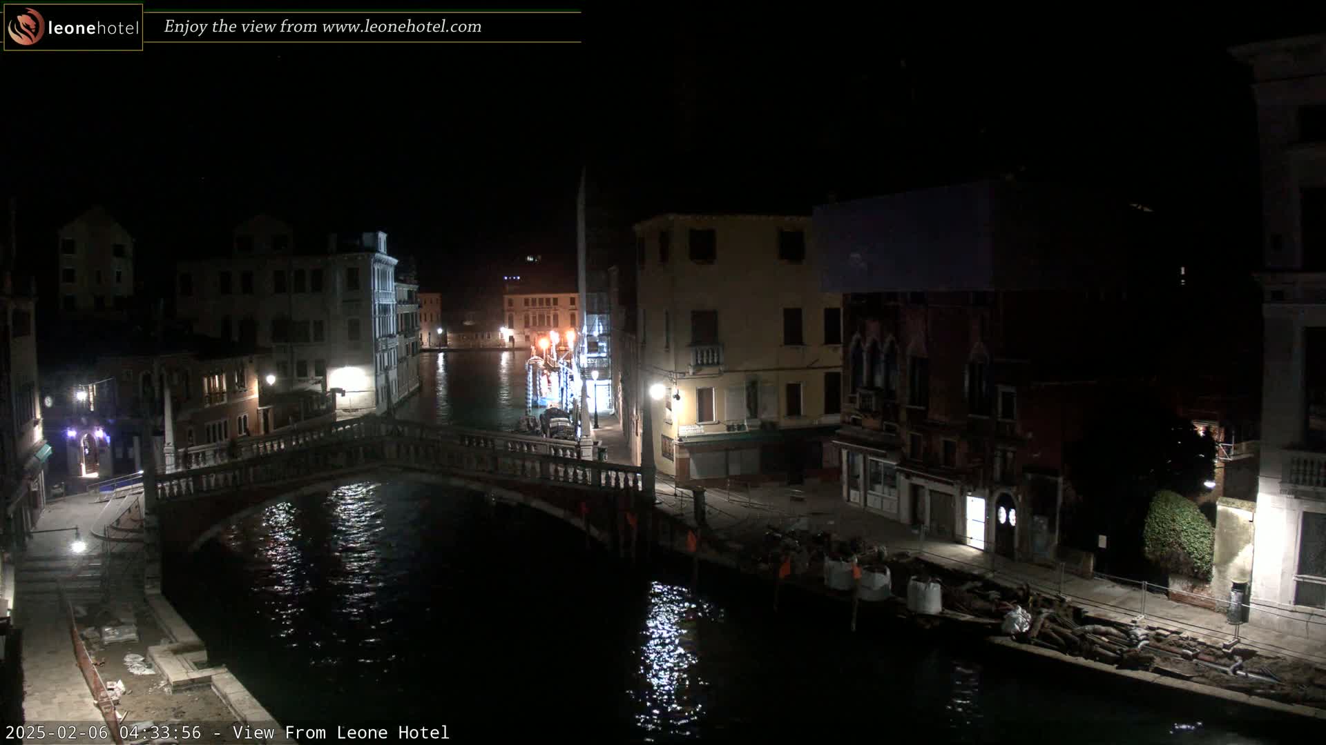 A nighttime view of a canal in Venice, showing a bridge, buildings, and some construction materials along the waterway.