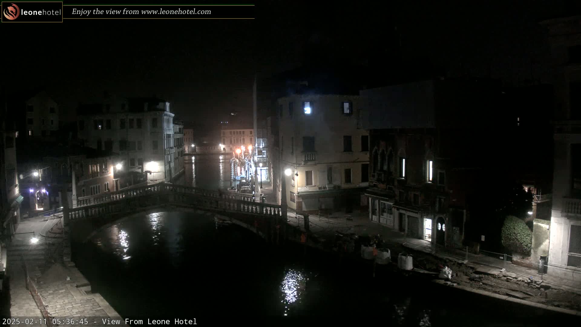 A nighttime view of a canal in Venice, showing bridges, buildings, and dimly lit streets.