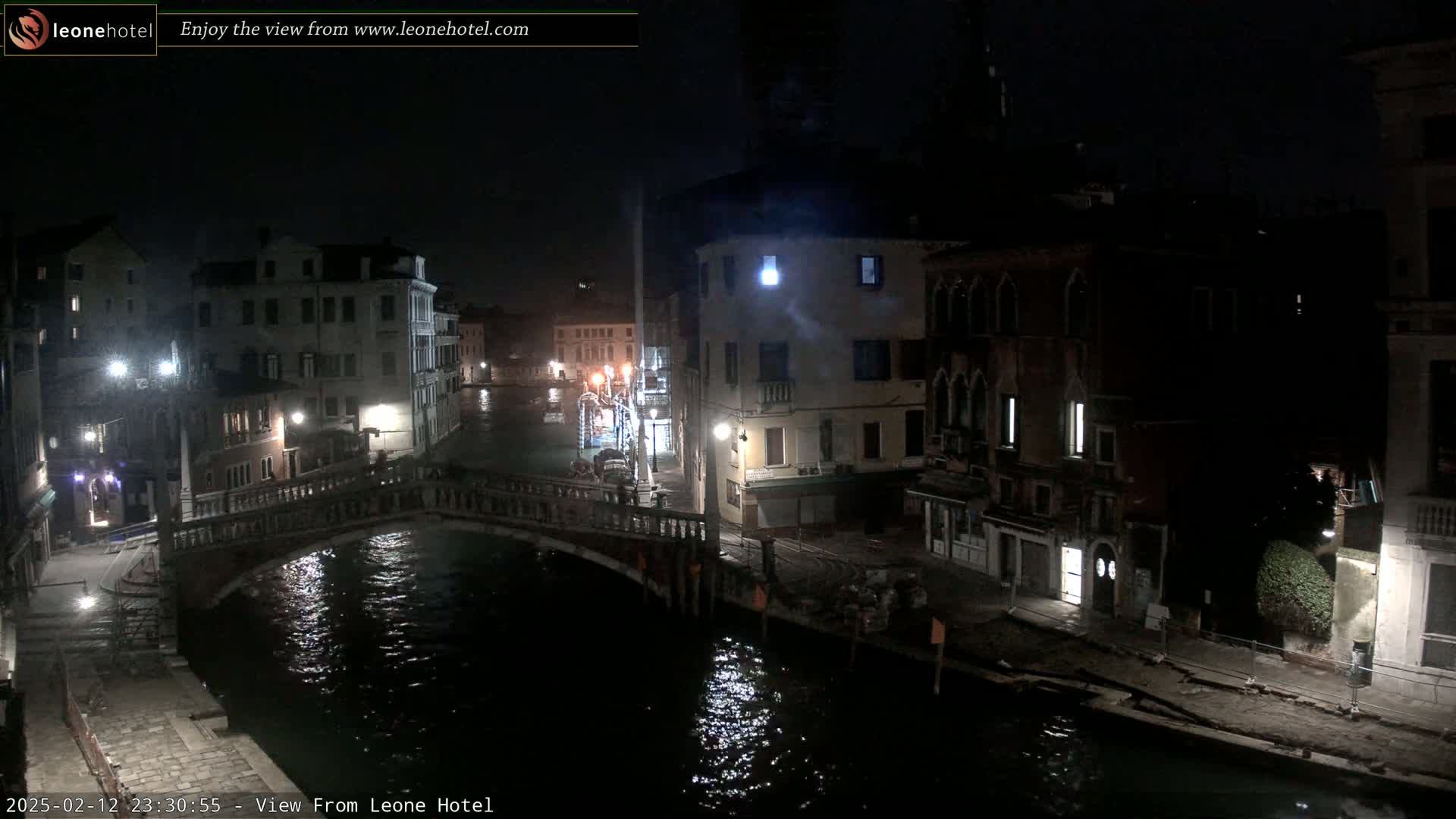 A nighttime view of a canal in Venice, Italy, showing a bridge and buildings along the water's edge under dark, possibly slightly overcast conditions.