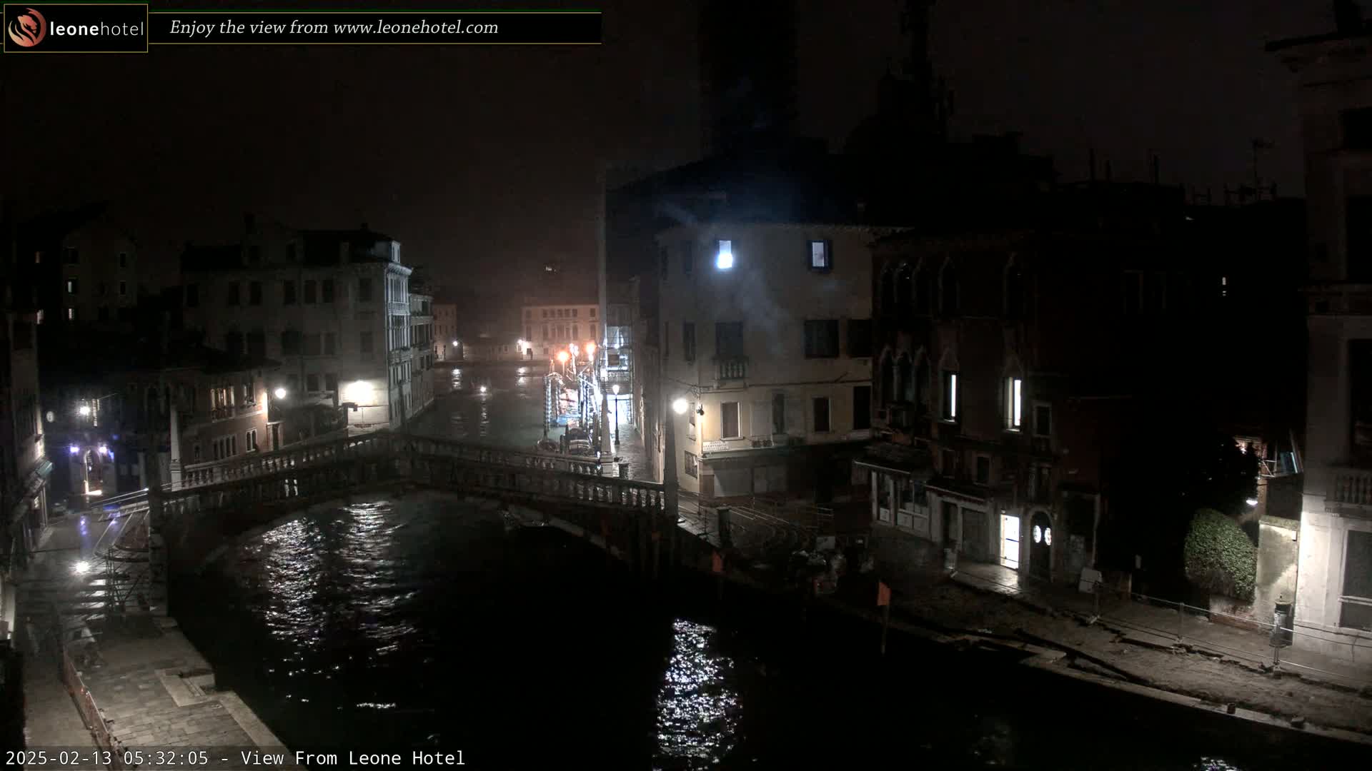 A nighttime view of a canal in Venice, Italy, with a bridge and buildings lining the waterway under dark, possibly overcast conditions.