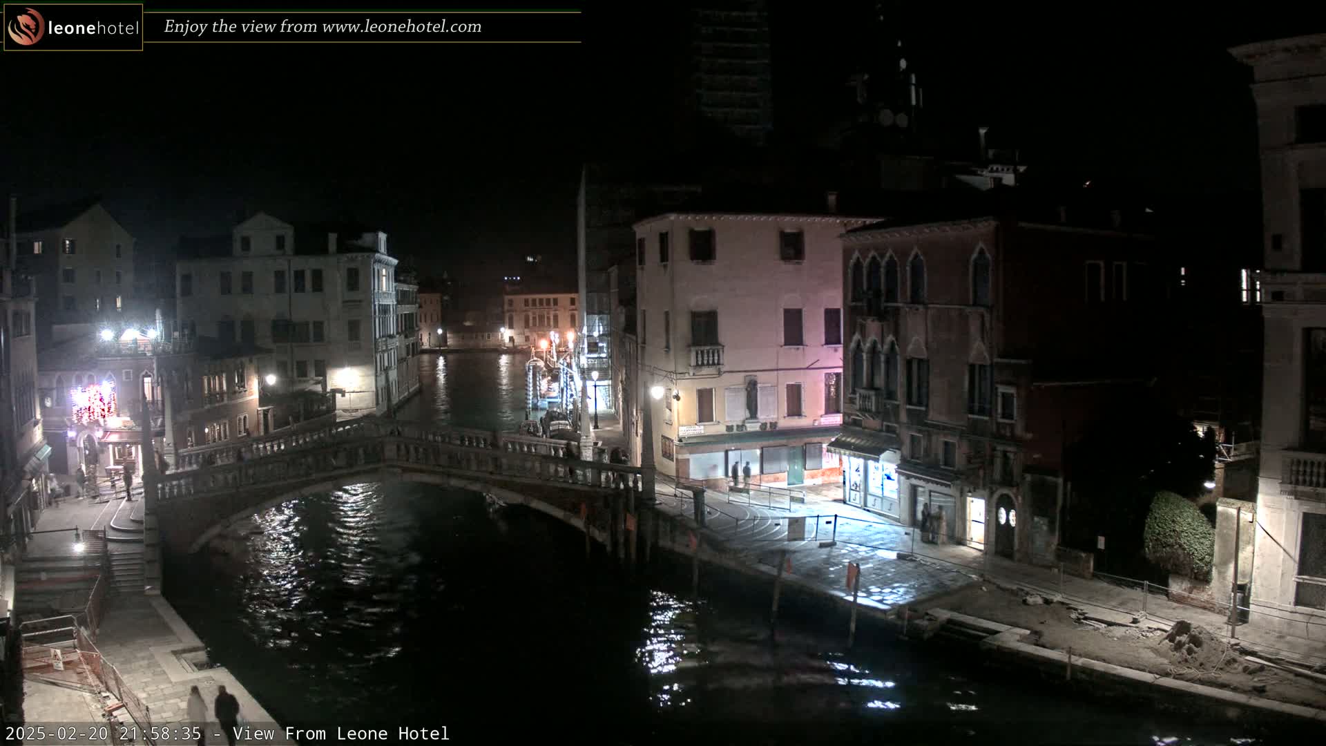 A nighttime view of a Venetian canal, showing bridges, buildings, and dimly lit streets.