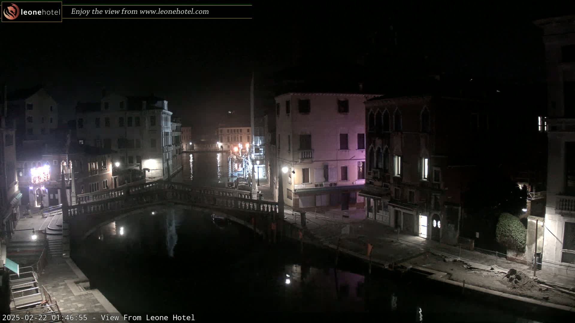A nighttime view of a canal in Venice, Italy, with buildings lining the waterway and a bridge spanning the canal.
