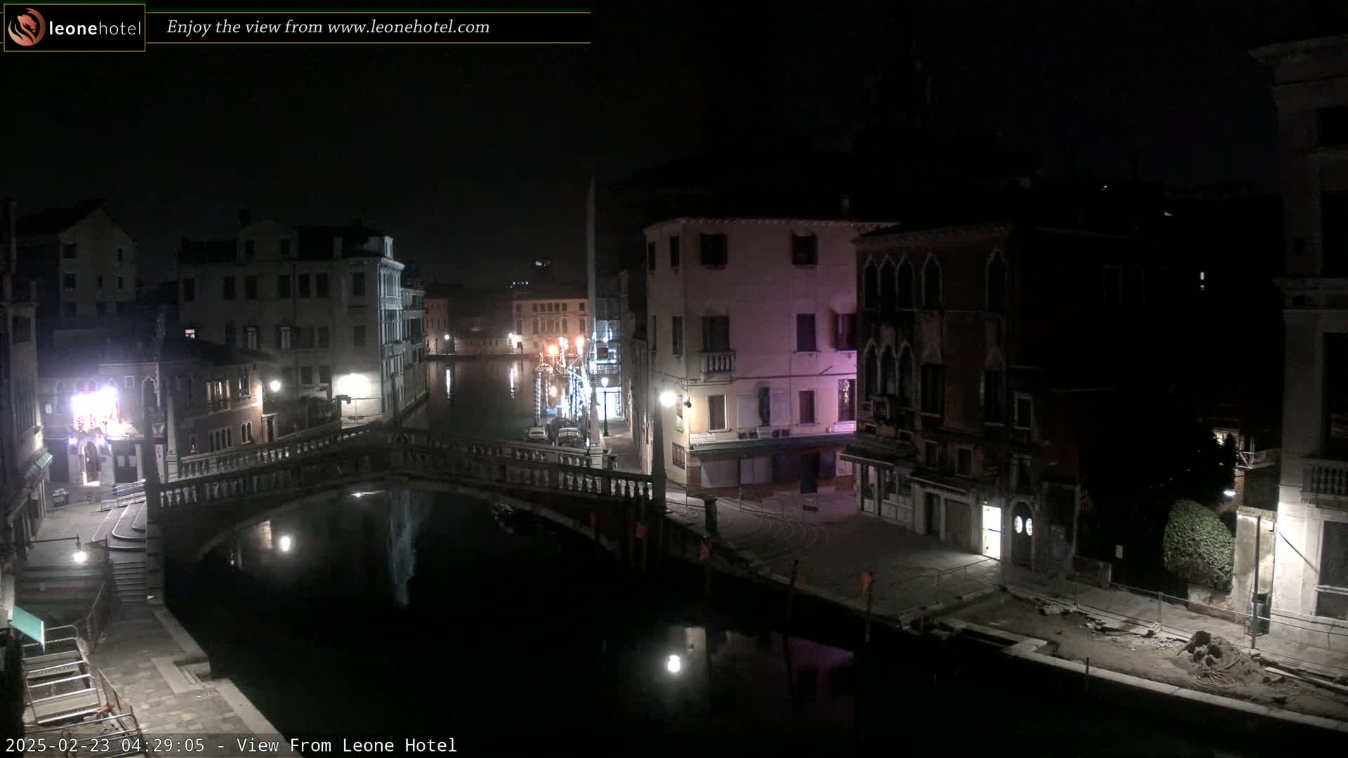 A nighttime view of a canal in Venice, Italy, showing several buildings along the waterway and a bridge crossing the canal.