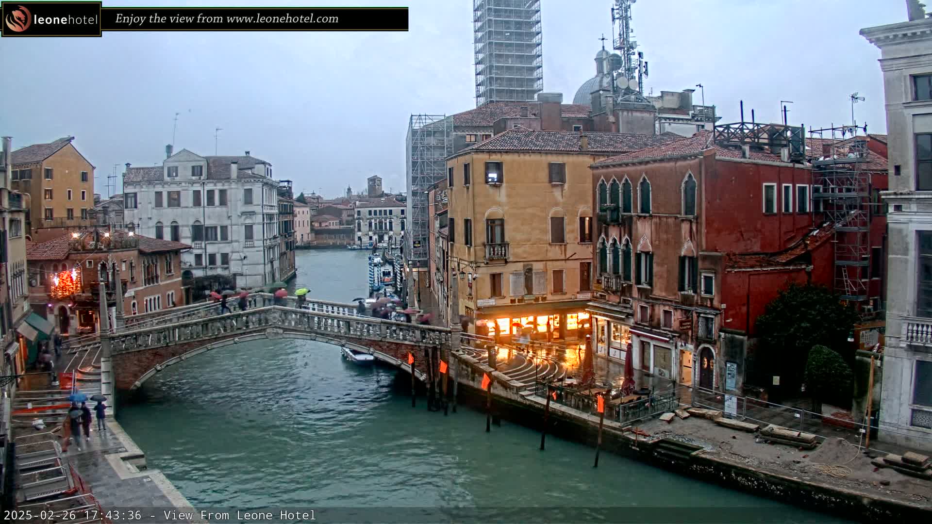 A bridge over a canal in Venice, Italy, with pedestrians crossing under an overcast sky.