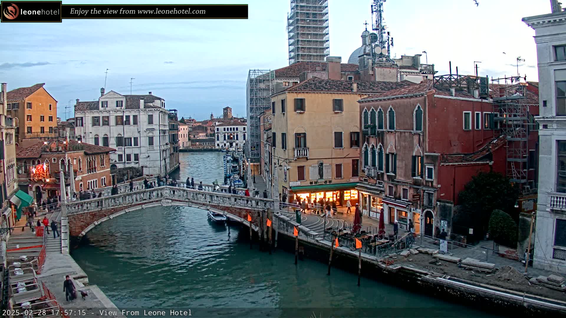 A stone bridge over a canal in Venice, Italy, is surrounded by colorful buildings under a twilight sky.