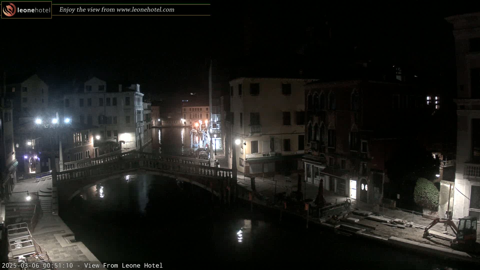 A nighttime view of a canal in Venice, Italy, showing bridges, buildings, and calm water.
