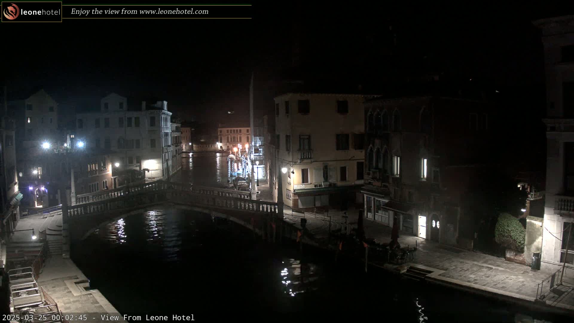 A nighttime view of a canal in Venice, Italy, with bridges, buildings, and dimly lit streets.