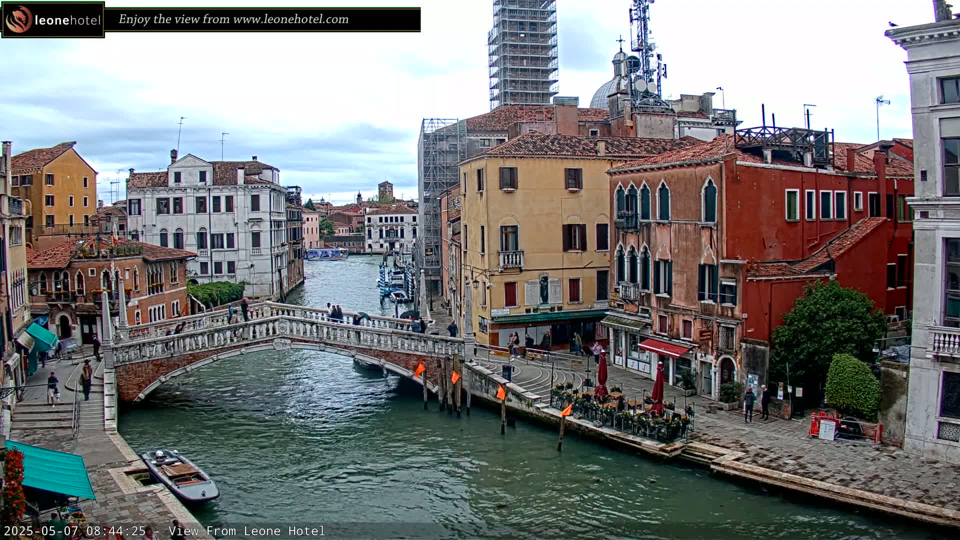 A canal in Venice, Italy, on an overcast day, is spanned by a stone bridge with several buildings lining its banks.