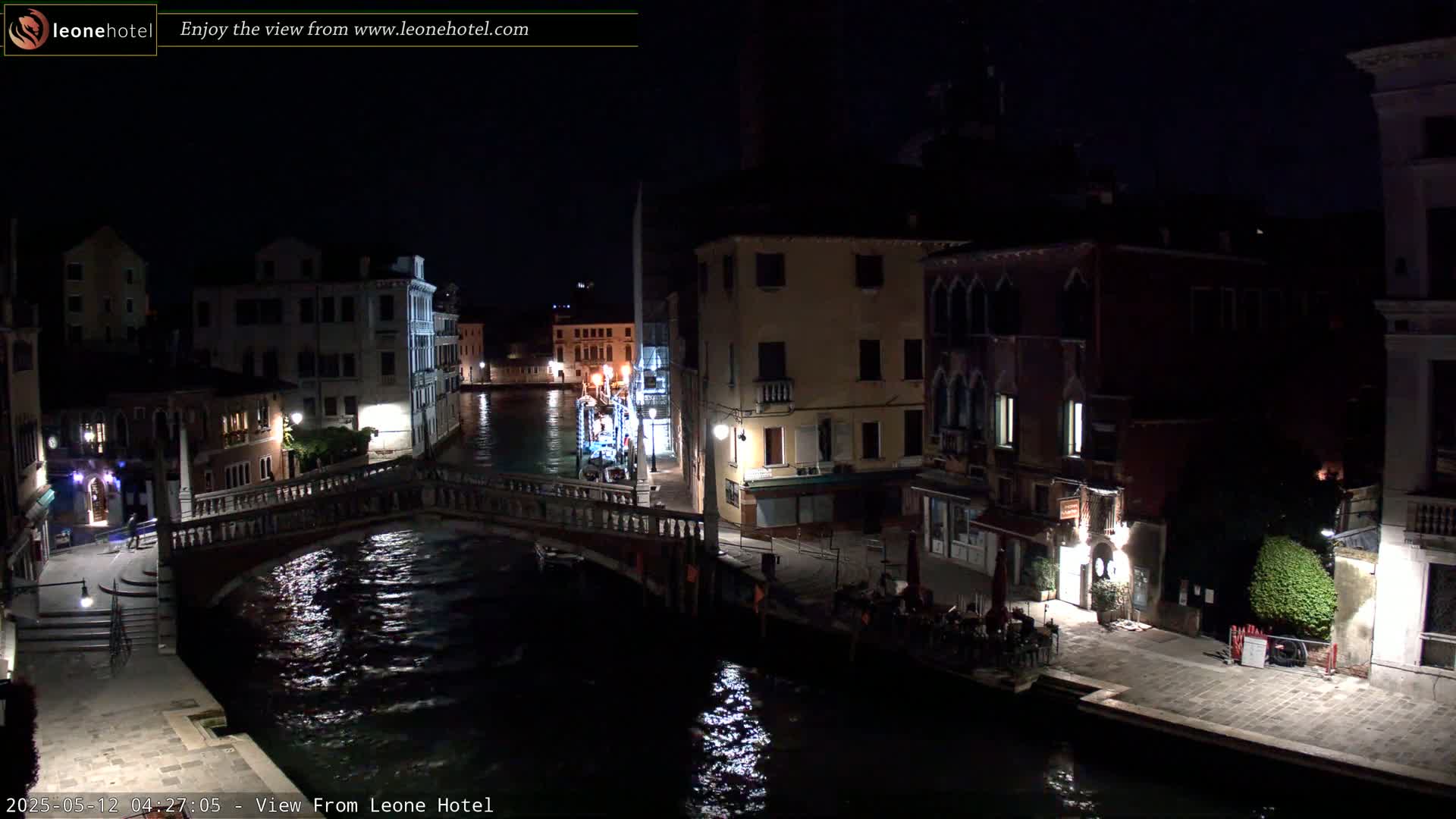 A nighttime view of a canal in Venice, showing bridges, buildings, and dimly lit walkways.