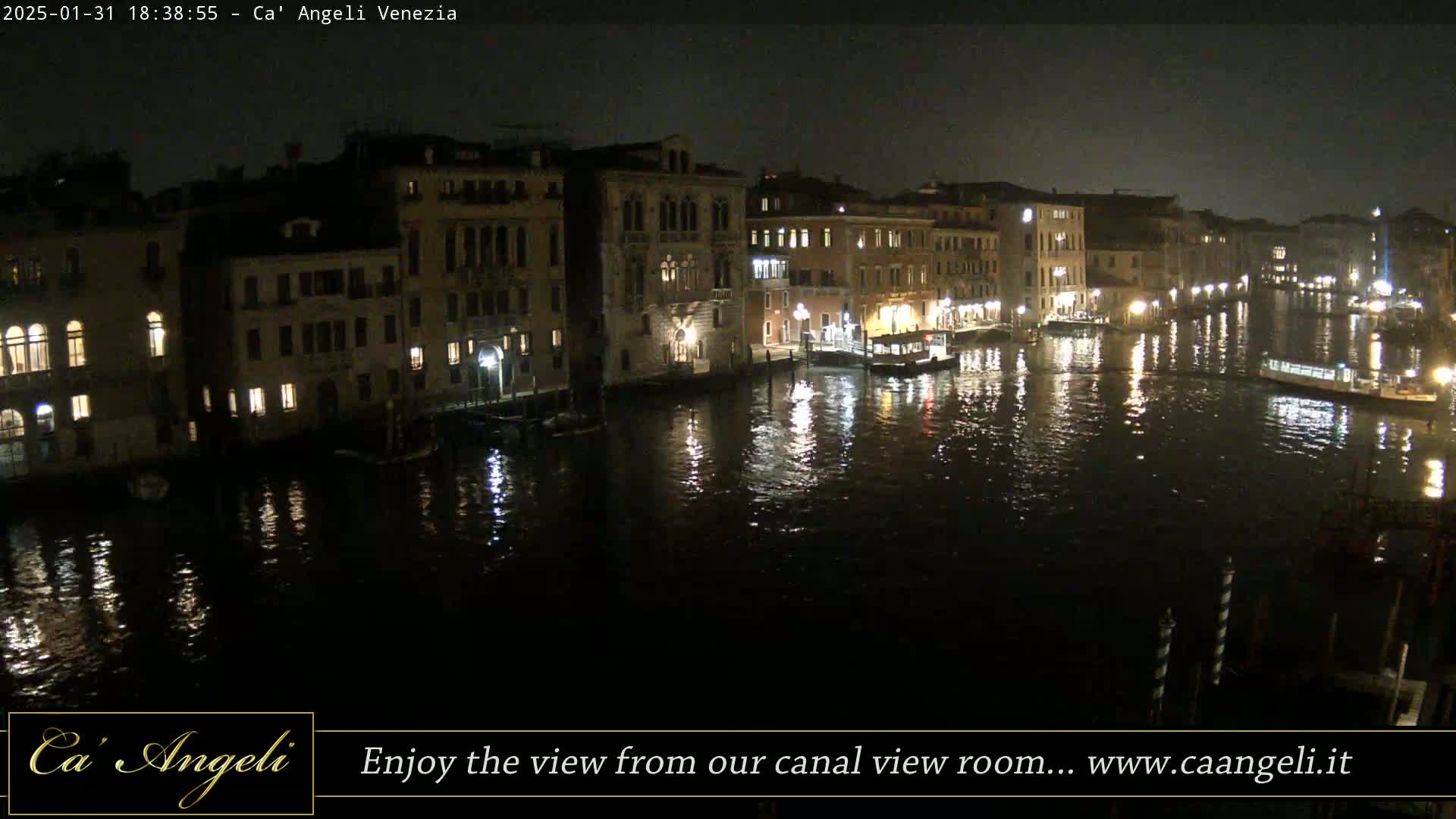 A nighttime view of a canal in Venice, with illuminated buildings lining the waterway and their lights reflecting on the calm water.