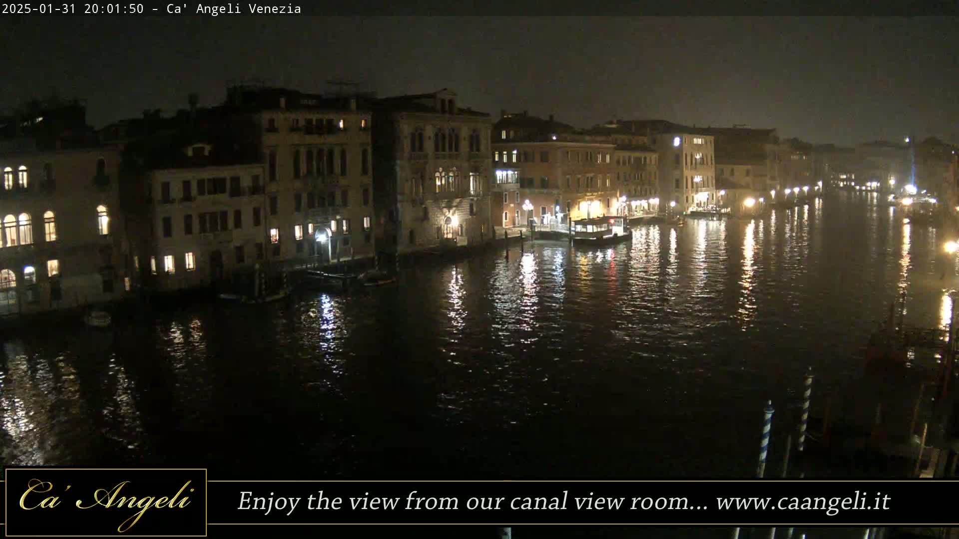 A nighttime view of a canal in Venice, with illuminated buildings lining the waterway and their lights reflecting on the calm water.