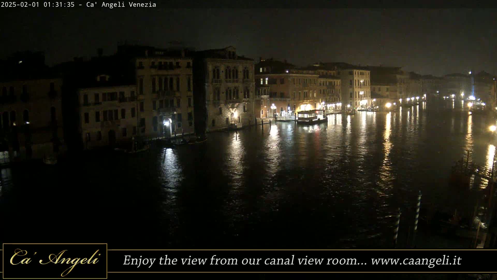 A nighttime view of a canal in Venice, with buildings illuminated along its banks and calm, reflective water.