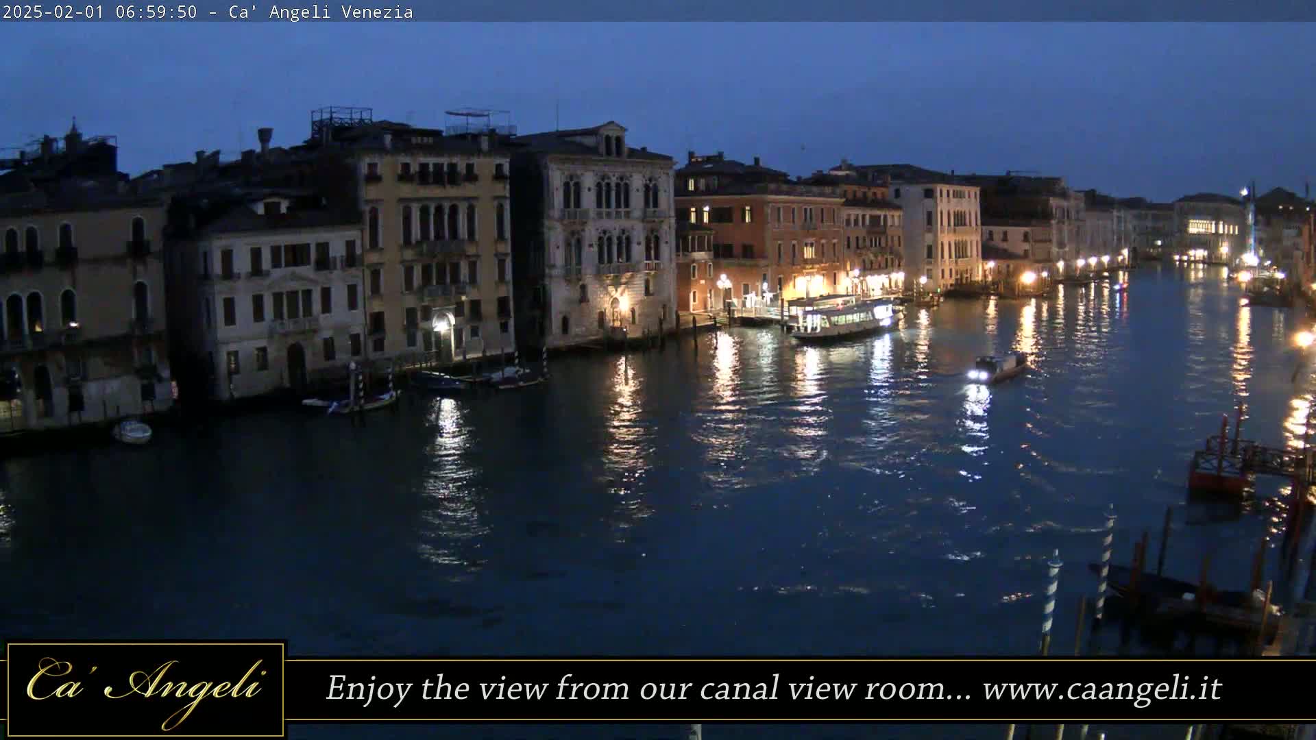 Nighttime view of a canal in Venice, Italy, with numerous buildings lining the waterway and boats on the water.