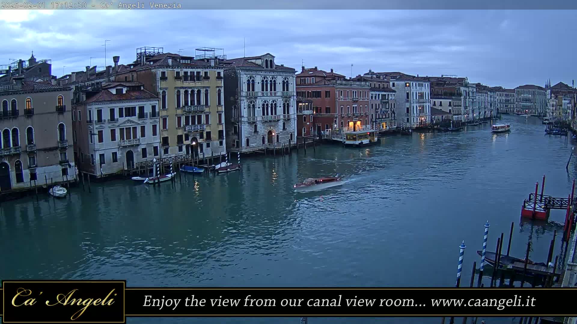 A wide shot shows a Venetian canal at dusk, lined with historic buildings, with several boats on the water under a cloudy sky.